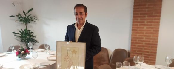 José Antonio Melgar posa, para Canal Charry, en el Restaurante Carrera Oficial, mostrando el Premio Puerta Nueva que ha recibido. // CharryTV