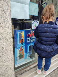 Una niña observa el cartel oficial del sorteo.  // CharryTV