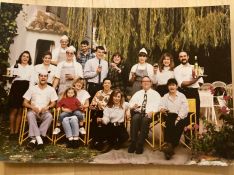 La pequeña Carmen sentada sobre uno de los trabajadores, con sus padres y resto de la plantilla a mediados de los años 90.  // CharryTV