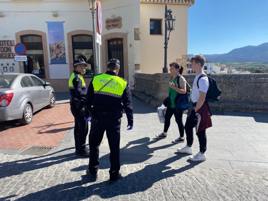 Dos agentes de la Policía Local piden a dos transeúntes que justifiquen su salida.