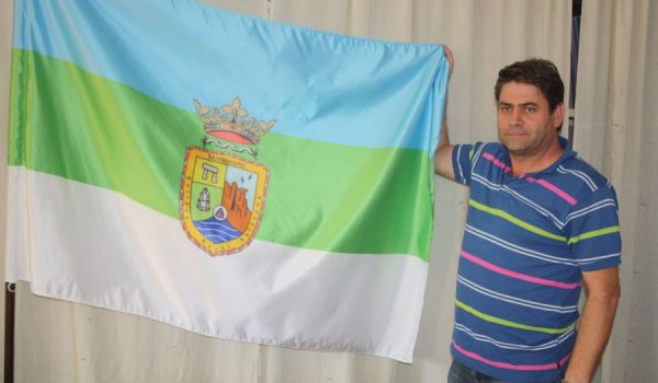 Un vecino muestra la bandera y el escudo de Montecorto.