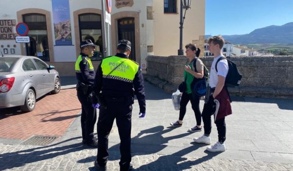 Dos agentes de la Policía Local piden a dos transeúntes que justifiquen su salida.