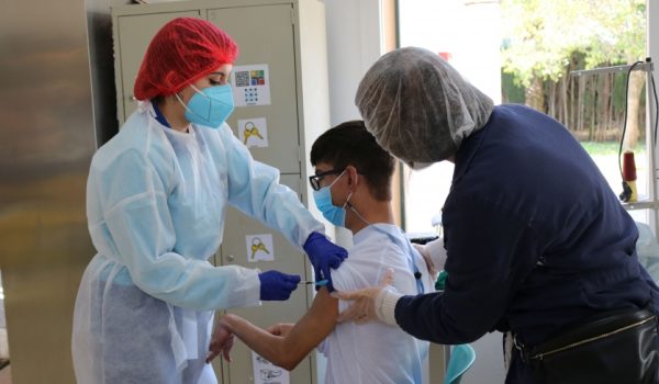 Dos profesionales sanitarias aplican la vacuna a uno de los usuarios