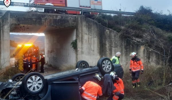 Una dotación de bomberos tuvo que intervenir para excarcelar al conductor del coche, que quedó volcado tras la caída