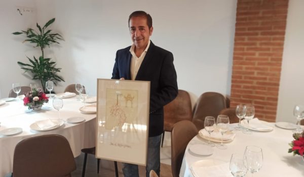 José Antonio Melgar posa, para Canal Charry, en el Restaurante Carrera Oficial, mostrando el Premio Puerta Nueva que ha recibido.