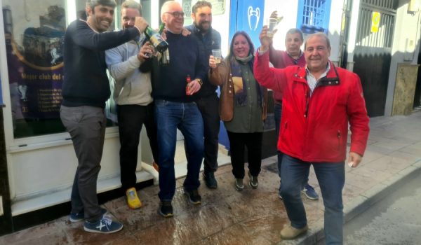 Rondeños celebran con champán en la puerta de la sede de la Peña Madridista que les ha tocado un tercer premio.