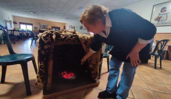 Ani introduce un brasero en una de las mesas del salón prinicipal.